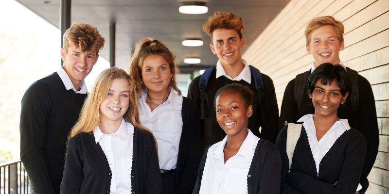 A diverse group of students in school uniforms smiling, symbolizing unity and respect.