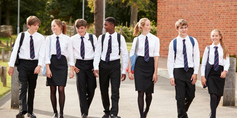 A group of diverse students in school uniforms walking together outside a Catholic school